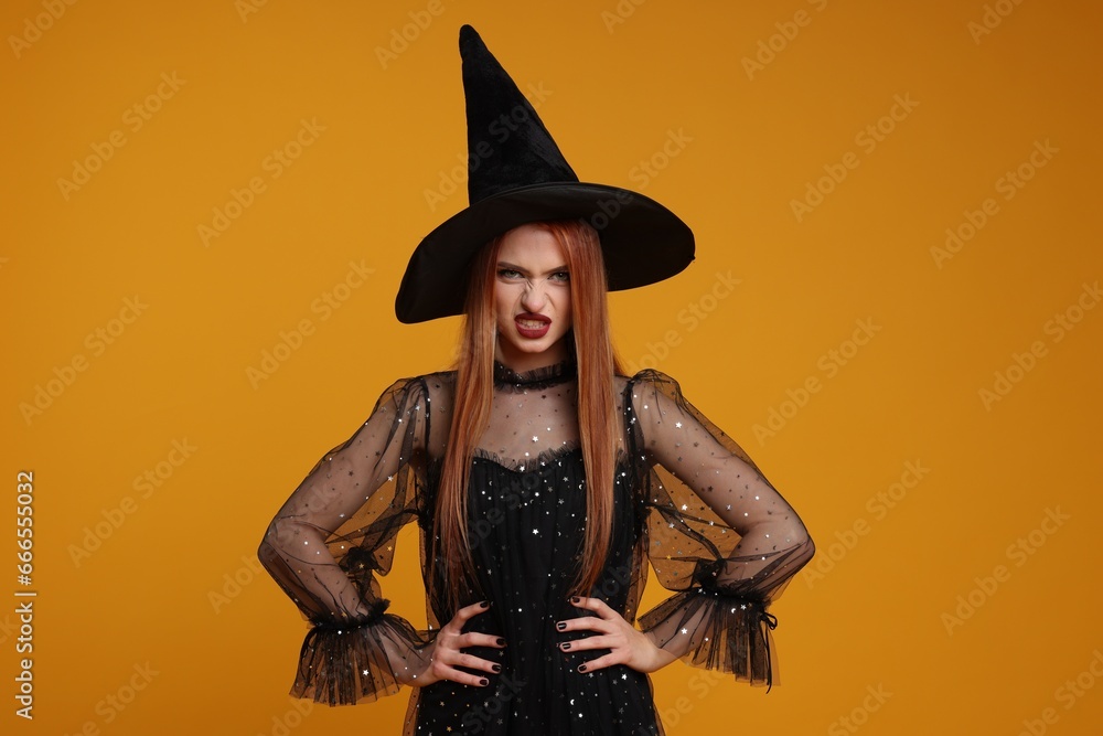 Young woman in scary witch costume on orange background. Halloween celebration Young woman in scary witch costume on orange background. Halloween celebration