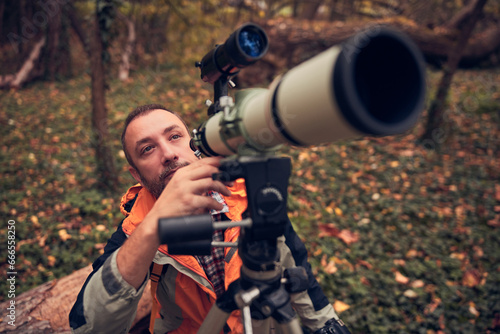 man using telescope for bird and animal watching in nature. photo