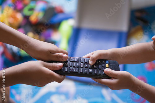 sibling fight over tv remote in a messy living room photo