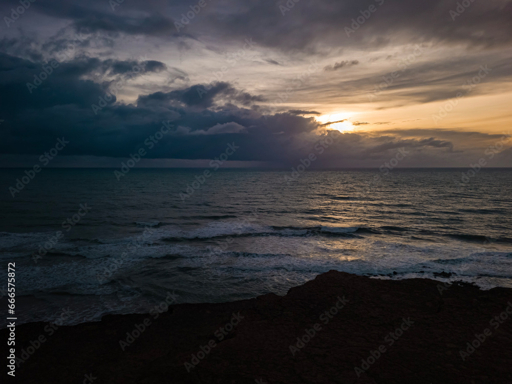 sunrise in the ocean with blue and orange sky with dramatic clouds seen from the cliff, at Pipa beach - Brazil sunrise in the ocean with blue and orange sky with dramatic clouds seen from the cliff, at Pipa beach - Brazil