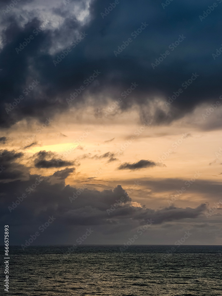 sunrise in the ocean with blue and orange sky with dramatic clouds seen from the cliff, at Pipa beach - Brazil