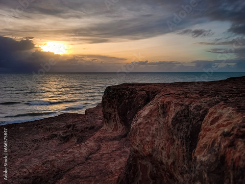 sunrise in the ocean with blue and orange sky with dramatic clouds seen from the cliff, at Pipa beach - Brazil © willamsharking