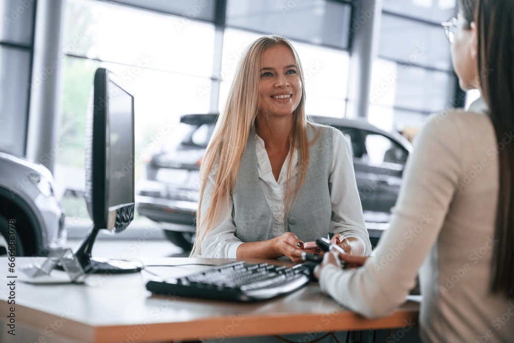 Female manager is helping woman customer in the car dealership salon Female manager is helping woman customer in the car dealership salon
