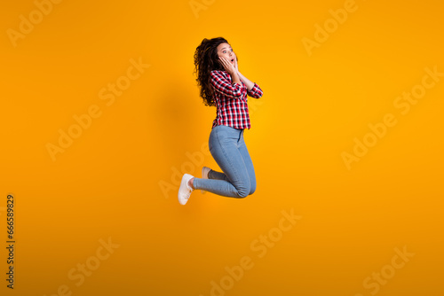 Full size photo of impressed woman with wavy hairdo dressed checkered shirt hands on cheeks look empty space isolated on yellow background photo