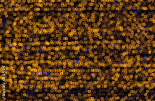 Bokeh made of bright orange lights, interspersed with blue. A large orange garland with rare blue lights in a blur.