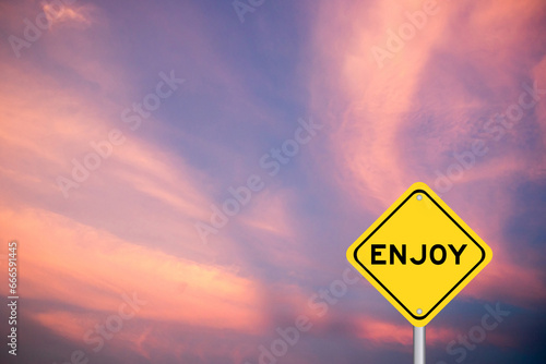 Yellow transportation sign with word enjoy on violet color sky background