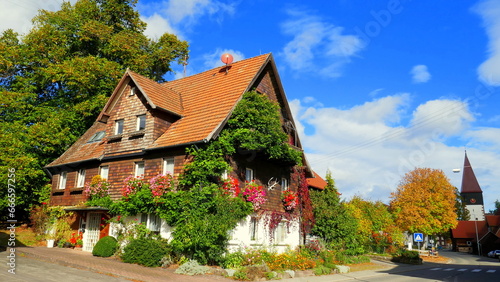 Wallpaper Mural traditionelles altes Wohnhaus mit Blumenschmuck im Herbst an Dorfstraße mit Kirche im Nordschwarzwald Torontodigital.ca