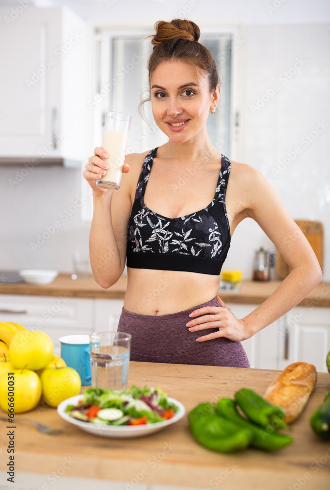 Positive young woman drinking dairy product at home