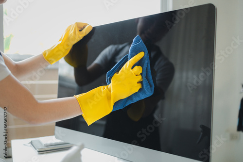 Cleaner is working, Wear rubber gloves and an apron to work, Cleaning staff wiping down office equipment, Wipe the monitor clean with a towel and sanitizer, cleaning idea.