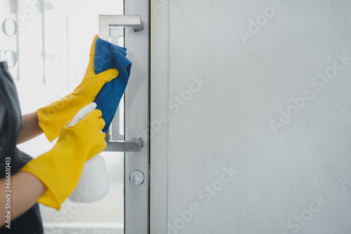 Housekeeper cleaning the furniture at home, Wear an apron and rubber gloves to protect against cleaning chemicals, female wiping down door handle with cleaning spray, cleaning idea.