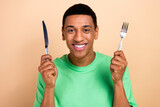 Photo portrait of handsome young male hold fork knife eating food wear trendy green outfit isolated on beige color background