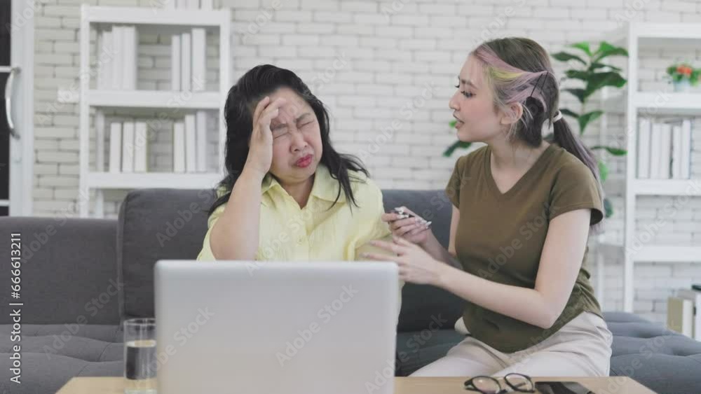 young asian daughter gives medicine to her elderly mother to relieve headaches young asian daughter gives medicine to her elderly mother to relieve headaches