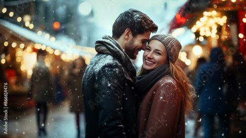 Happy young couple loving each other standing against the backdrop of christmas fair lights on street, wearing coats in snow