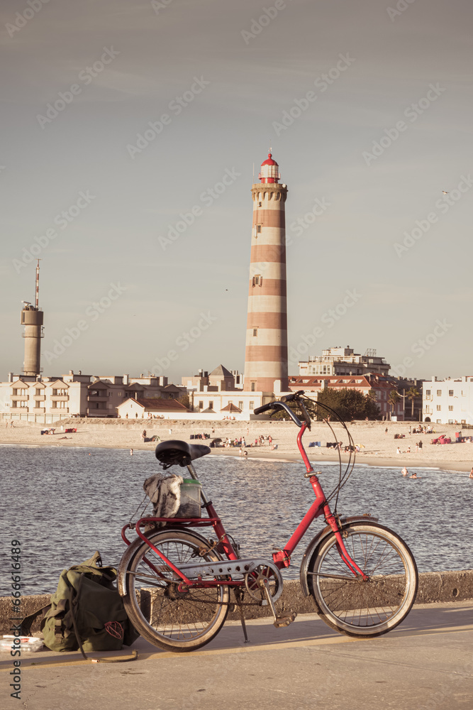 A red bicycle standing and Costa Nova's lighthouse, Aveiro, Portugal