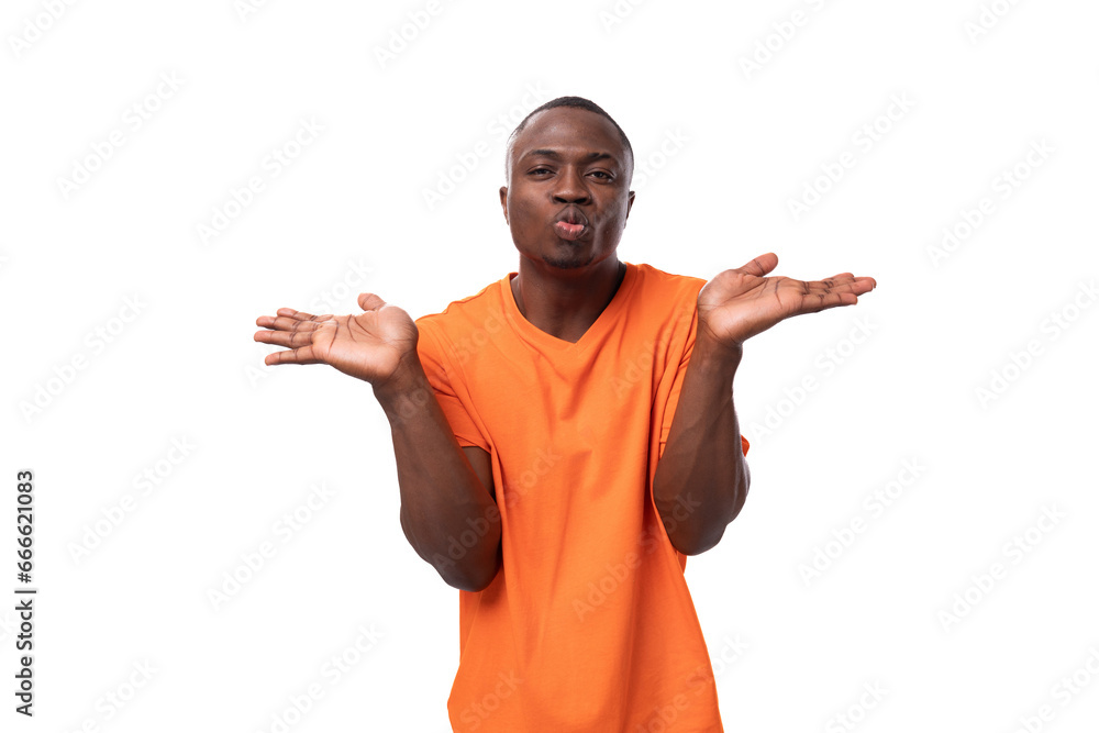 a young handsome American man dressed in an orange t-shirt is having doubts. corporate clothing concept a young handsome American man dressed in an orange t-shirt is having doubts. corporate clothing concept