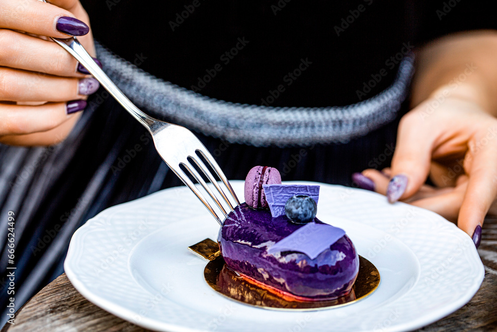 Hand, fork and eating chocolate dessert. Closeup, cake on plate. Closeup woman's hand hold a fork to slice of chocolate cake. Hand taking bite of chocolate cake with fork closeup
