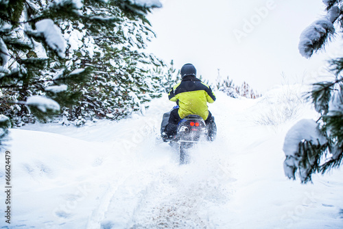 Snowmobile in snow. Concept winter sports. Man is riding snowmobile in mountains. Pilot on a sports snowmobile in a mountain forest. Athlete rides a snowmobile in the mountains