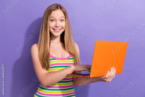 Portrait of intelligent teen girl with long hairstyle wear colorful singlet holding laptop write email isolated on purple background
