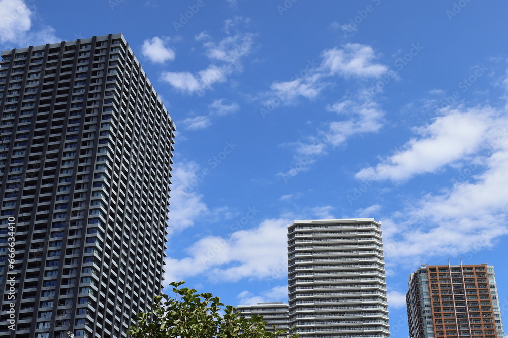 快晴の青空と雲にそびえる高層マンション群：都会の街並み