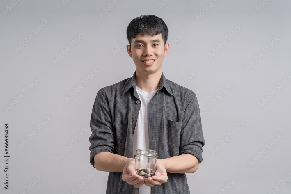 Handsome man holding the glass jar with lots of coins inside for save money. Handsome man holding the glass jar with lots of coins inside for save money.