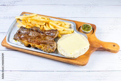 Obraz na płótnie Tray of roasted haunch tip, accompanied by arepa with cheese, French fries and chimichurri
w salonie