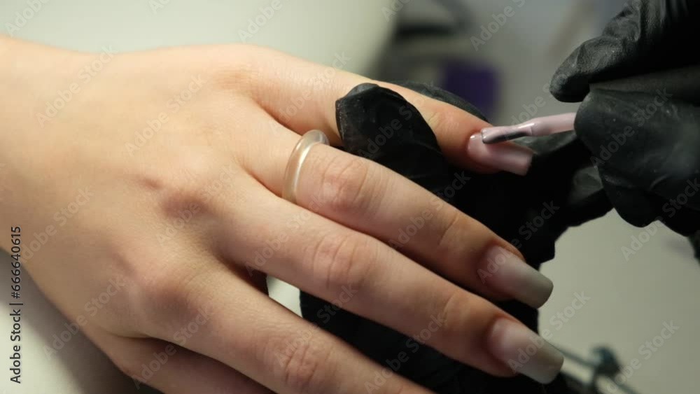 Female hands and tools for manicure, process of performing manicure in beauty salon. Nail care procedure in a beauty salon. Gloved hands of an experienced manicurist in gloves are varnished nails Female hands and tools for manicure, process of performing manicure in beauty salon. Nail care procedure in a beauty salon. Gloved hands of an experienced manicurist in gloves are varnished nails