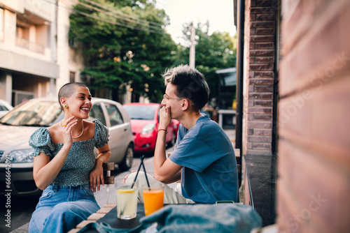 Lesbian couple talking and cuddling in cafe. Two beautiful young woman sitting next each other and sharing sweet moments.