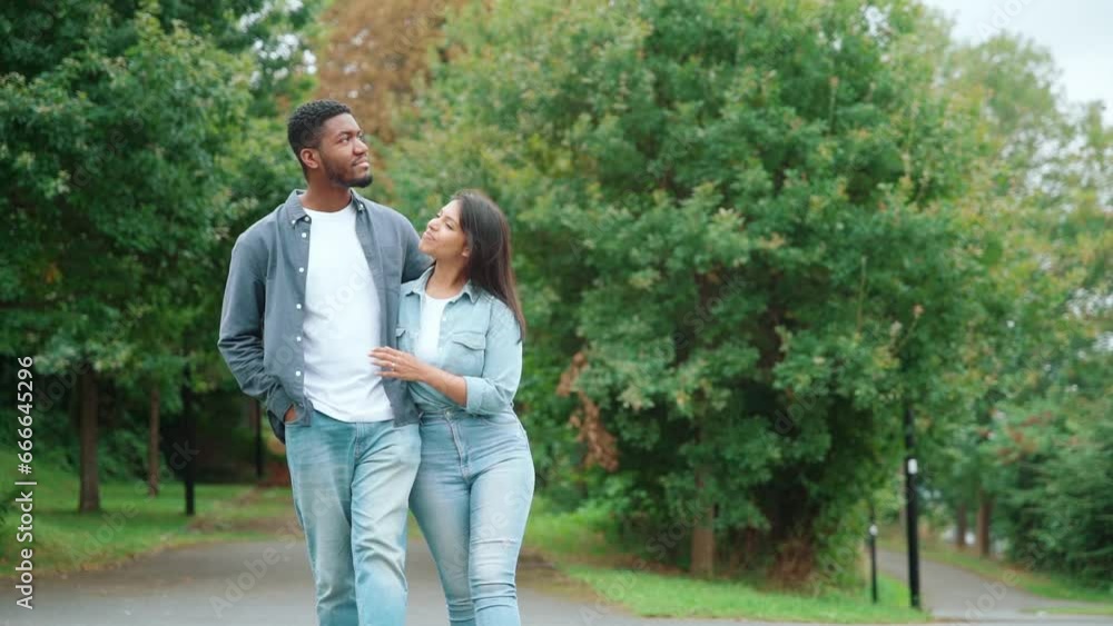 handsome african man and a beautiful indian woman walking in park in city on summer day handsome african man and a beautiful indian woman walking in park in city on summer day