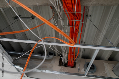 Fotografía orange network cables run bundled under the ceiling.