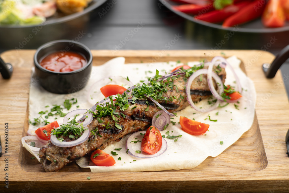 Lula kebab with vegetables and pita bread on a wooden board at restaurant. Arabic cuisine Lula kebab with vegetables and pita bread on a wooden board at restaurant. Arabic cuisine