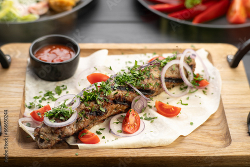 Lula kebab with vegetables and pita bread on a wooden board at restaurant. Arabic cuisine