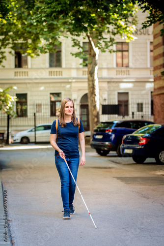 Portrait of blind woman with white cane walking on the street