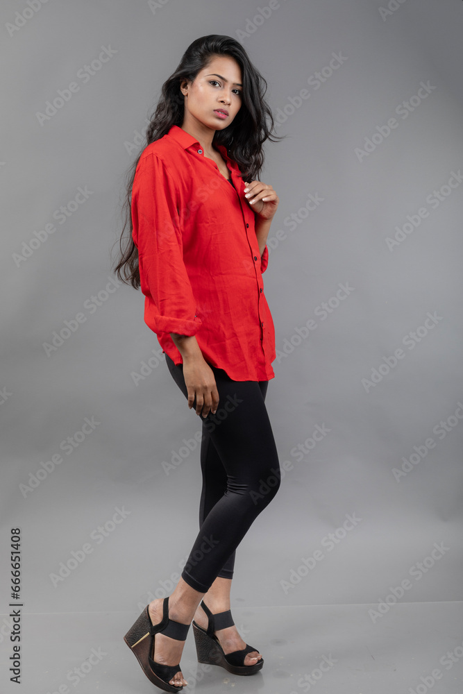Indian young female model in casual wear against grey background - stock photo. Long black haired model wearing red shirt and black jeans. Indian young female model in casual wear against grey background - stock photo. Long black haired model wearing red shirt and black jeans.