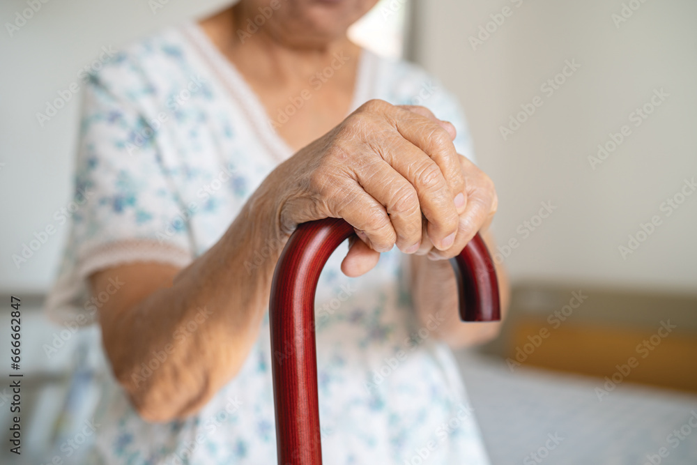 Asian elderly disability woman holding waling stick, wood cane, round handle, walking aid for help to walk. - obrazy, fototapety, plakaty 