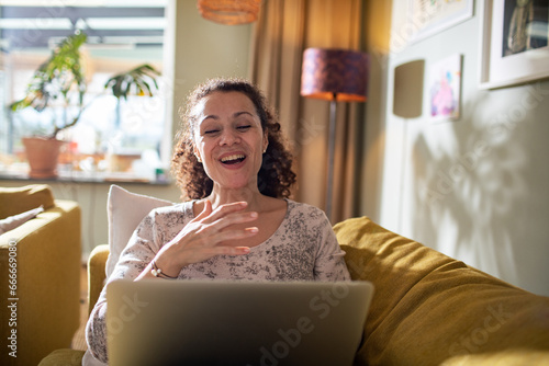 Hispanic woman using the laptop on the couch at home photo