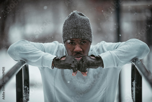 Young man working out in a outdoor gym at the park during winter photo