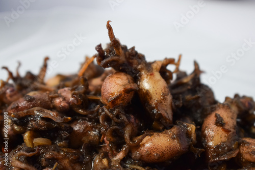 Close up Tumis Cumi, Oseng cumi or Stir Fried Squid placed on tranparent plate of glass isolated on white background. Indonesian food 