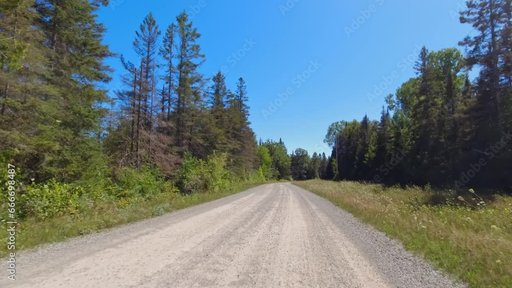 Front view forward driving Plate on a gravel road. POV driving car view. Rural winding road with tree lined forest. Sunny afternoon blue sky. Empty winding road ahead on Manitoulin Island, no traffic. Front view forward driving Plate on a gravel road. POV driving car view. Rural winding road with tree lined forest. Sunny afternoon blue sky. Empty winding road ahead on Manitoulin Island, no traffic.