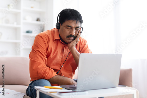 Tired indian man working from home, feeling sleepy