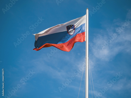 slovenian flag waving in wind against blue sky photo