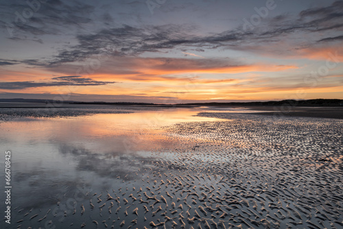 Sunset reflections on sandy beach at sunset, Camber Sands, East Sussex, England photo