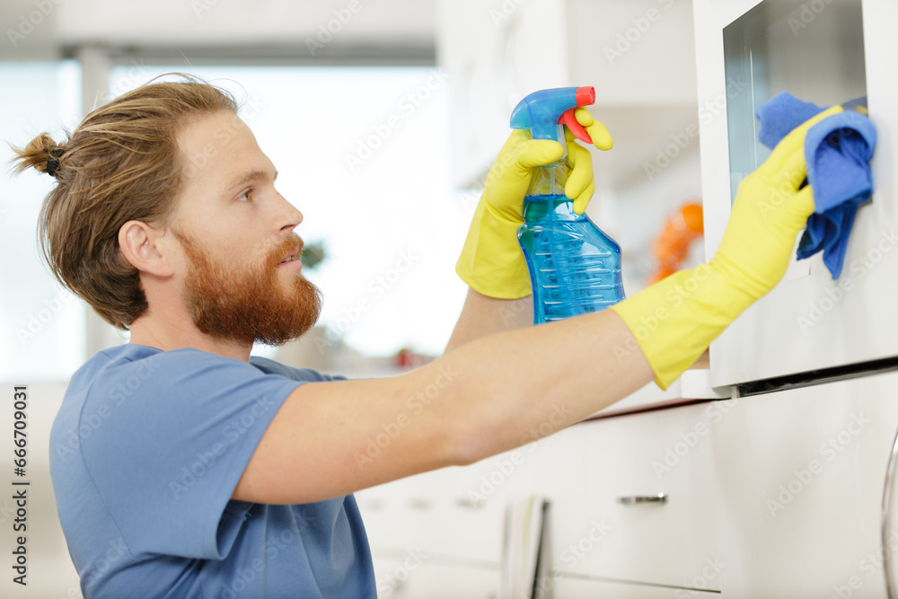 man spraying an oven in kitchen man spraying an oven in kitchen