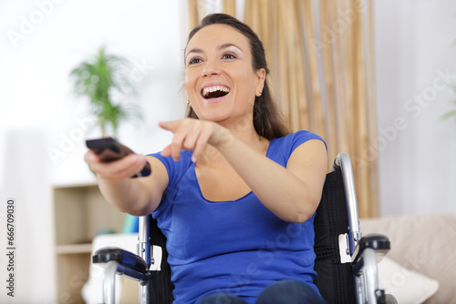 female in wheelchair elevision remote control pointing to tv