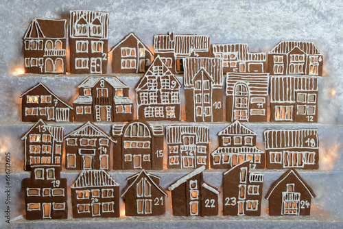 advent calendar out of 24 different home made gingerbread houses facade in rows illuminated with light from backside