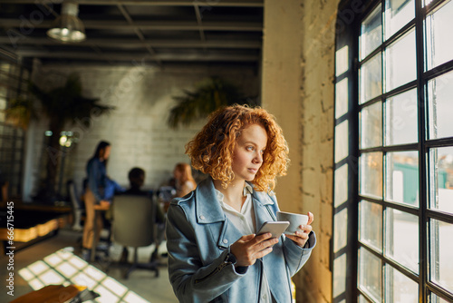 Young businesswoman looking out the window on a coffee break in the office photo