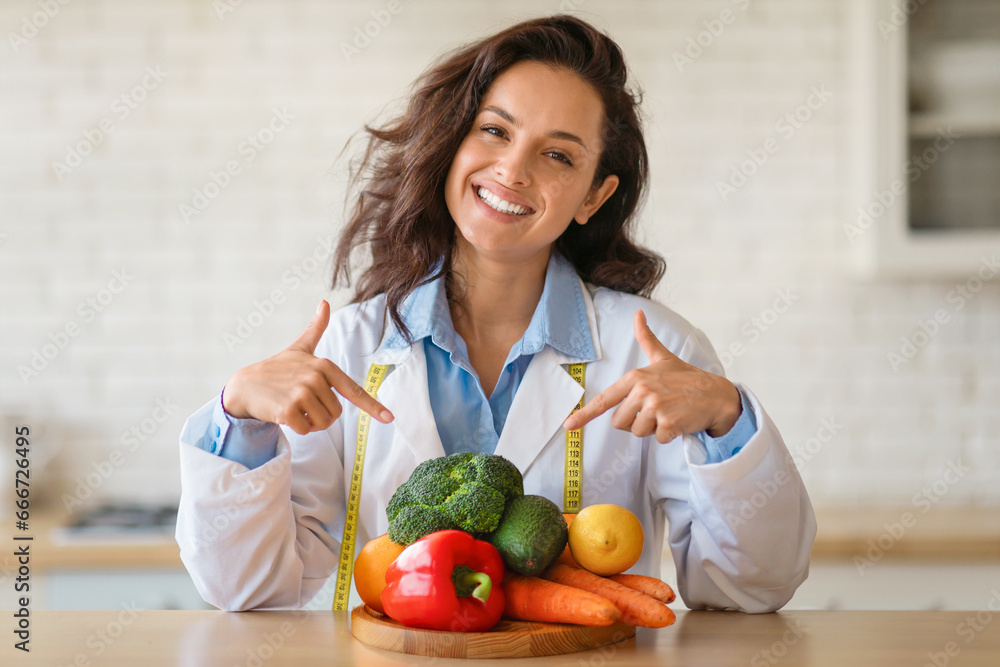 Happy dietitian pointing at fresh produce with tape measure Happy dietitian pointing at fresh produce with tape measure