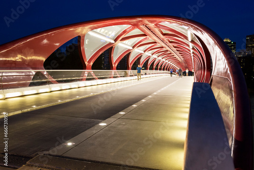 Glowing lights inside the Peace Bridge at night, a red steel pedestrian bridge going over the Bow River; Calgary, Alberta, Canada photo