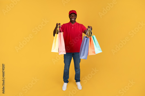 Happy millennial black guy courier hold many boxes with purchases