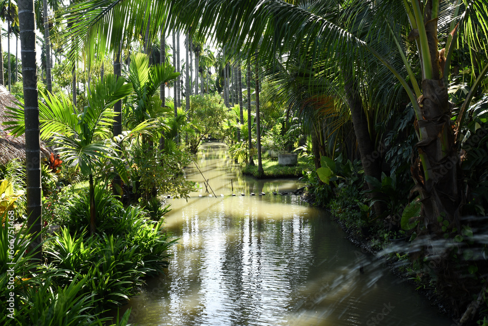 Fresh green garden, tropical style, with a canal in the middle between the trees. Fresh green garden, tropical style, with a canal in the middle between the trees.