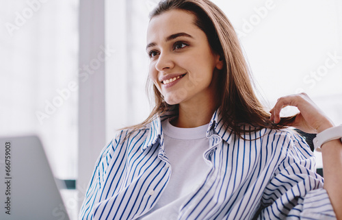 Satisfied woman in casual clothing browsing laptop at modern office